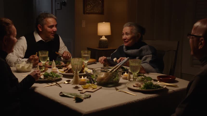 Men and women at the dinner table talking and smiling while eating