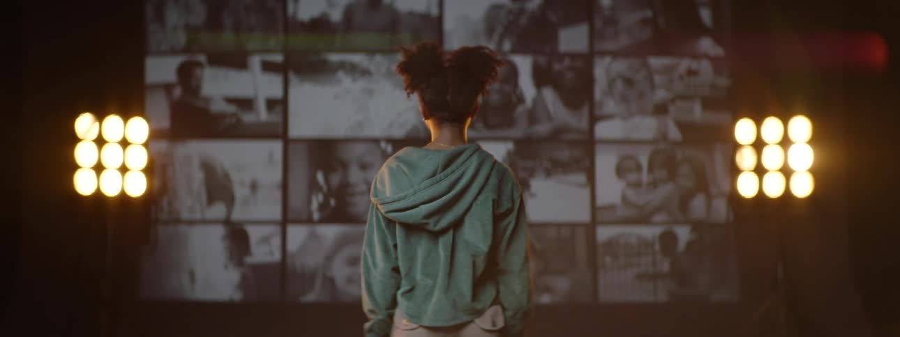 Young girl stands on a stage in front of a wall of screens
