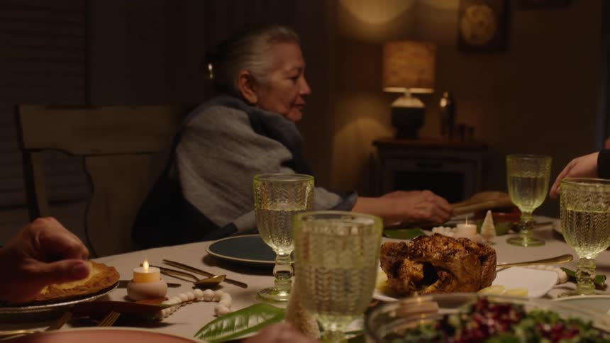 People sitting at a dining table at night serving themselves