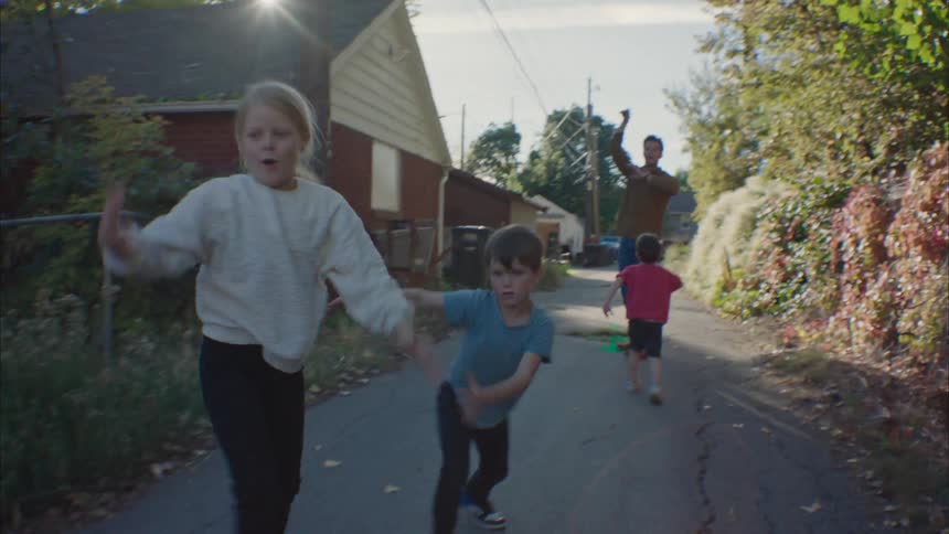 Father plays football with his kids in the street at morning