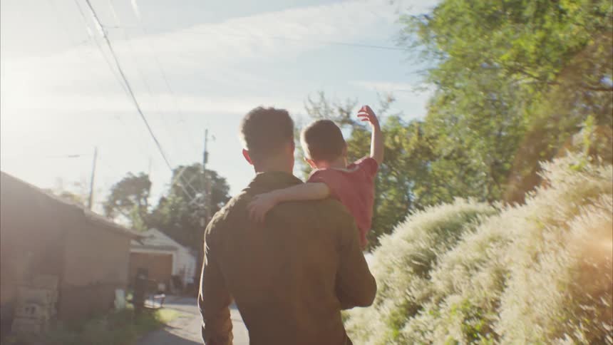 Father picking up his son and walking through the neighborhood