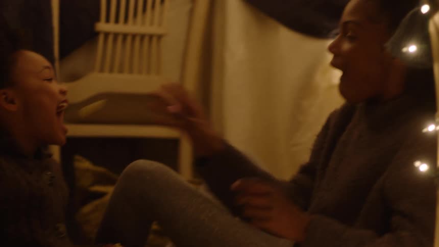 Teenage girl sitting next to another girl and playfully throwing popcorn into each others mouths