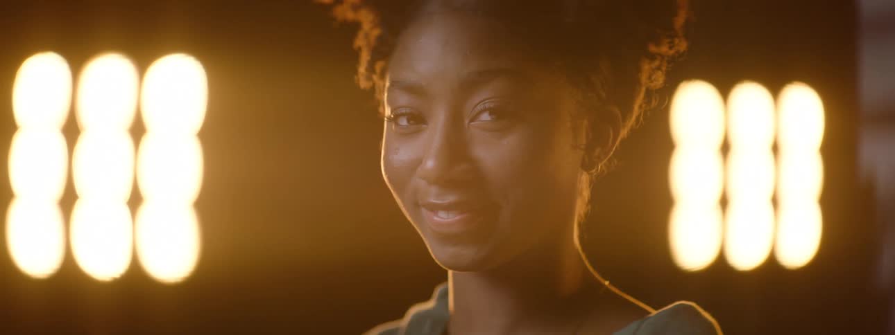 A womans face being illuminated by a light and she is smiling