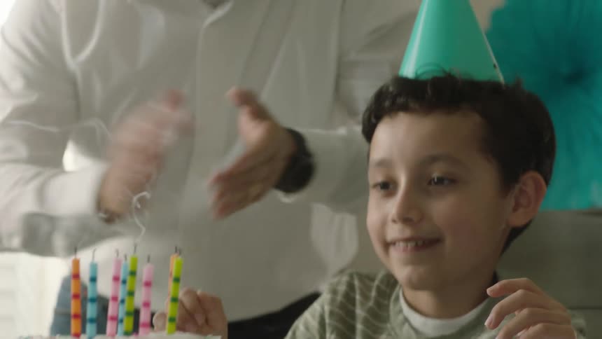 Parents celebrating their sons birthday as he blows out the candles on the cake