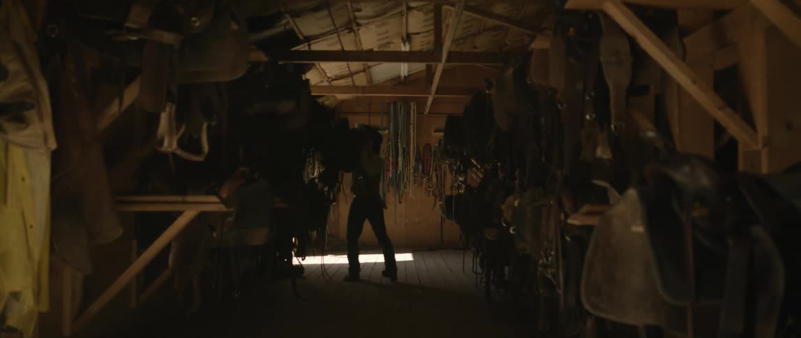 A man takes a saddle from the stable