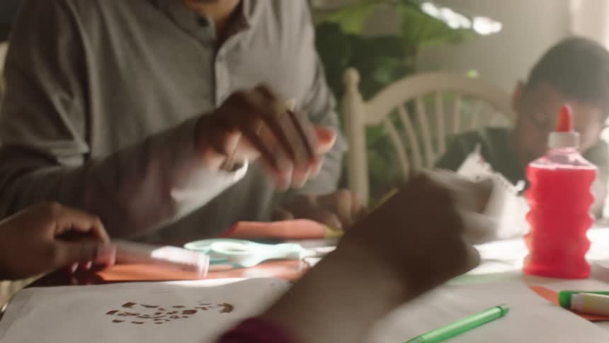 A father building some paper figure with his son and daughter