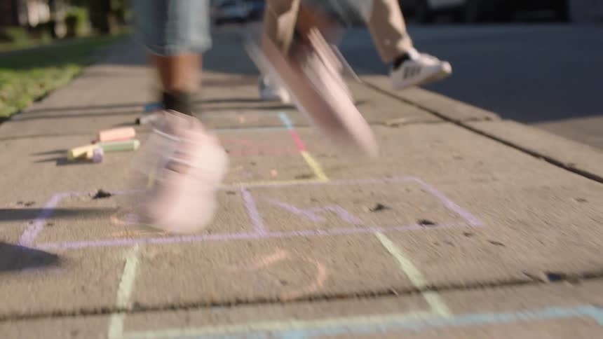 Legs of children playing on a sidewalk
