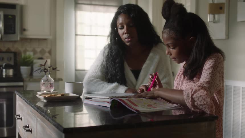 Mother helps daughter with homework in the kitchen