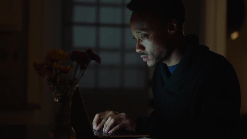 Man sitting at a table typing on his laptop