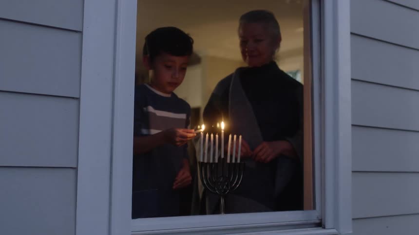 A clip of a mother and son lighting the candles by the window