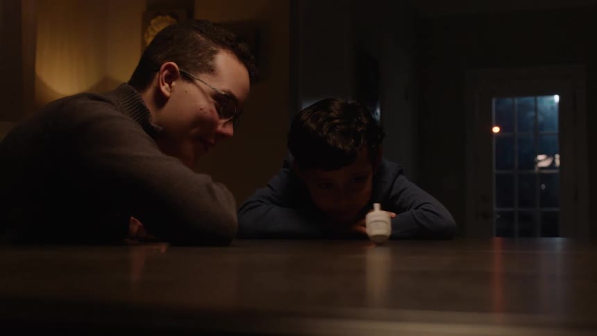 Two friends sitting at a table watching a spinning top