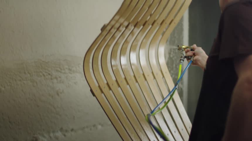 A man painting wooden furniture with spray paint