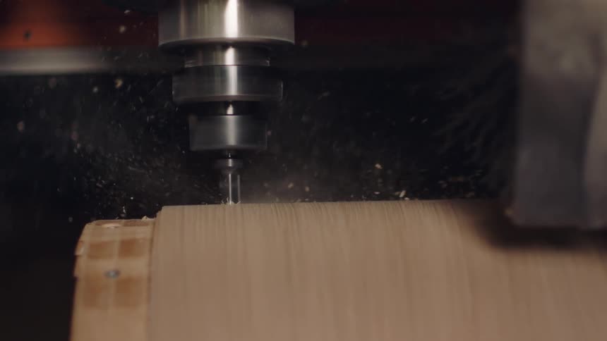 Closeup of a drill boring into wood with splinters flying in slow motion