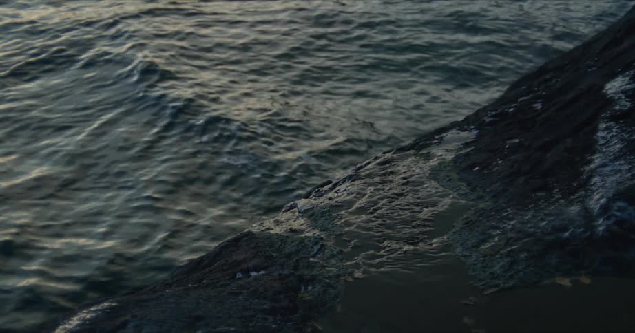 Morning light reflecting in small ripples on the sea by a rocky pier