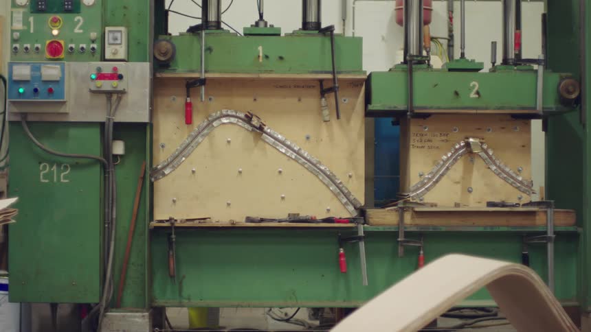 Worker operates a hydraulic press to form pieces