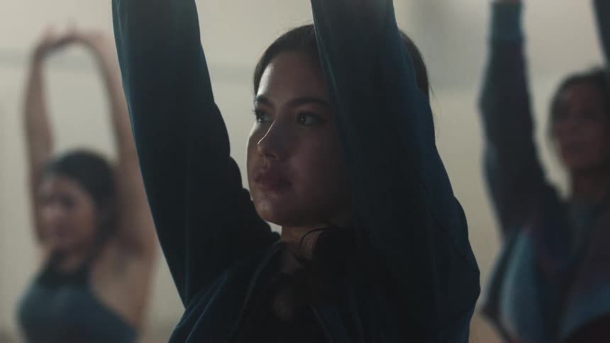 A woman is stretching her arms and wearing longsleeved clothes