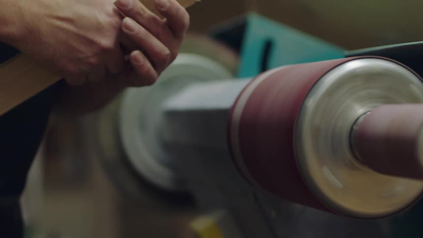 Person using a sander to sand a piece of wood