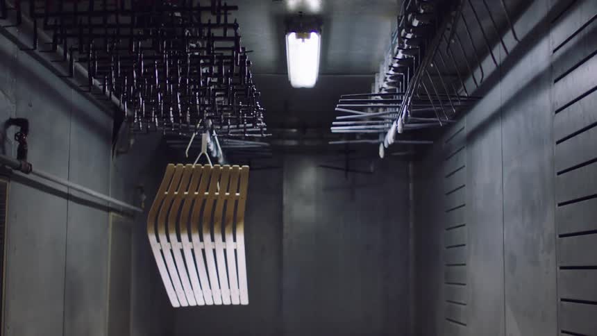 A wooden object hanging from a ceiling inside a concrete room