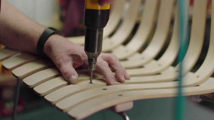 Man fix bolt on a chair with a machine during the day
