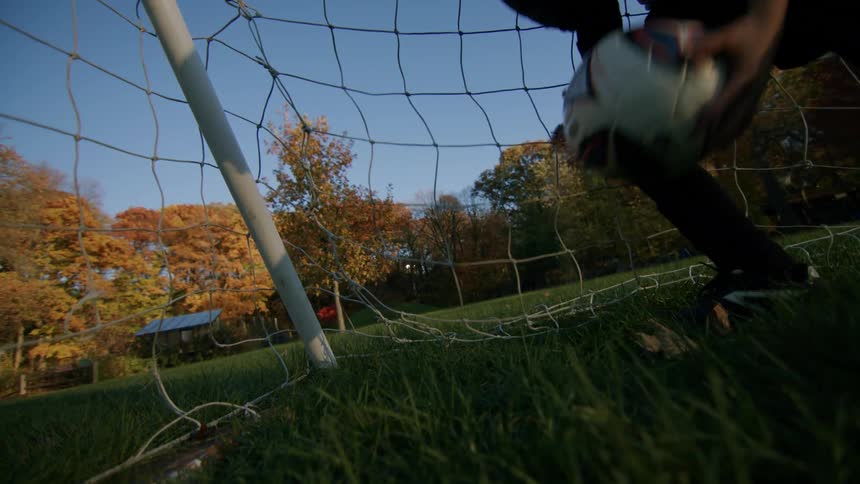 A person catching a soccer ball next to a net