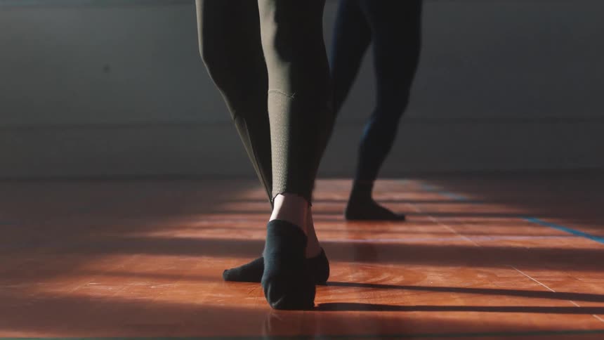 People performing ballet steps with socks on their feet