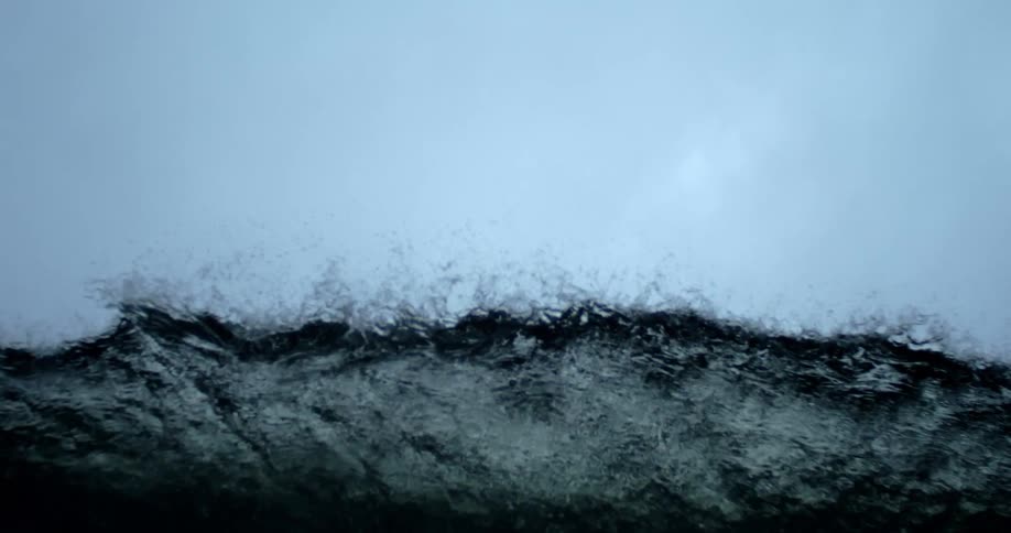 A wave of blue liquid with several drops going upwards