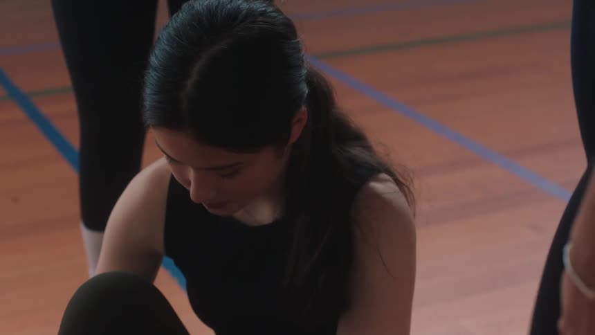 One dancer helps another to stand up in the dance studio