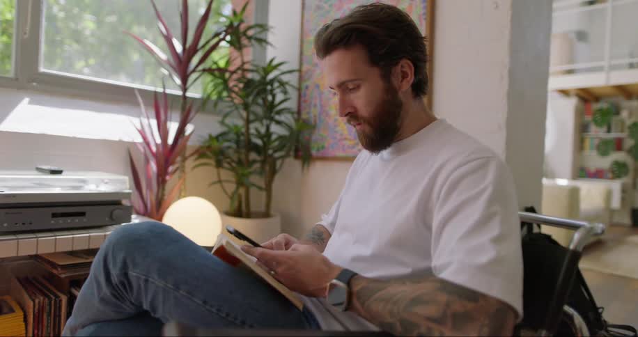 Portrait of a man sitting in a chair in an indoor setting at home engrossed in his cellphone
