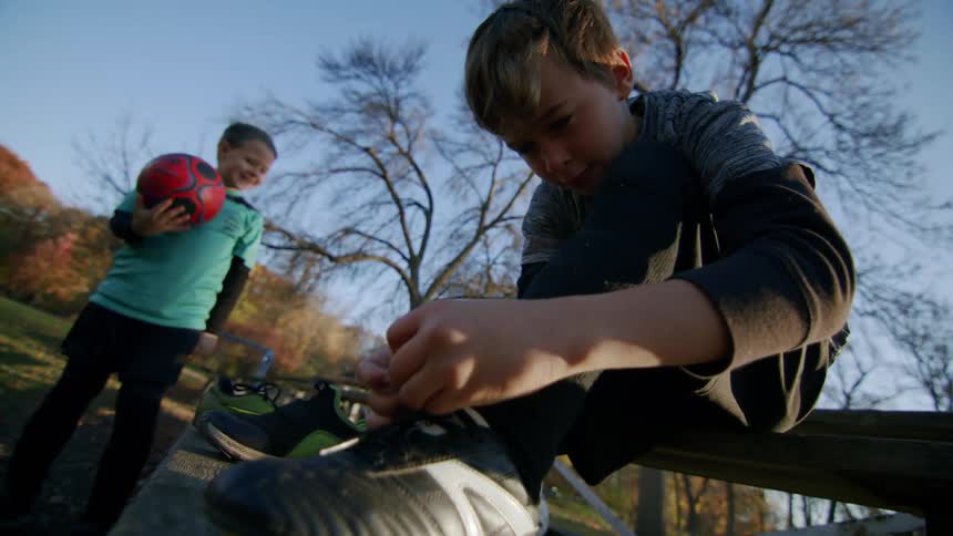 A child is tying his sneaker so he can play soccer