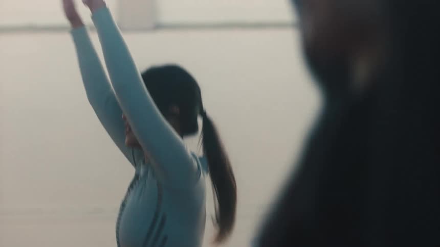 Two women exercise by performing jumping jacks