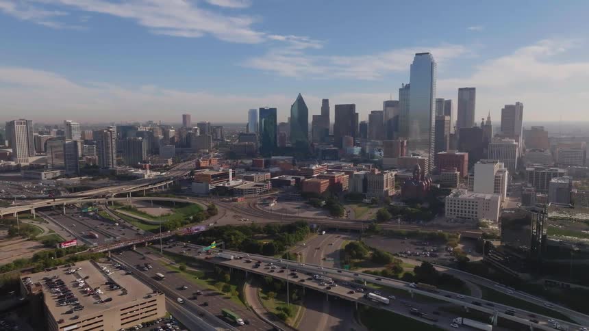 An aerial view of a metropolitan city with tall buildings and a street with many vehicles