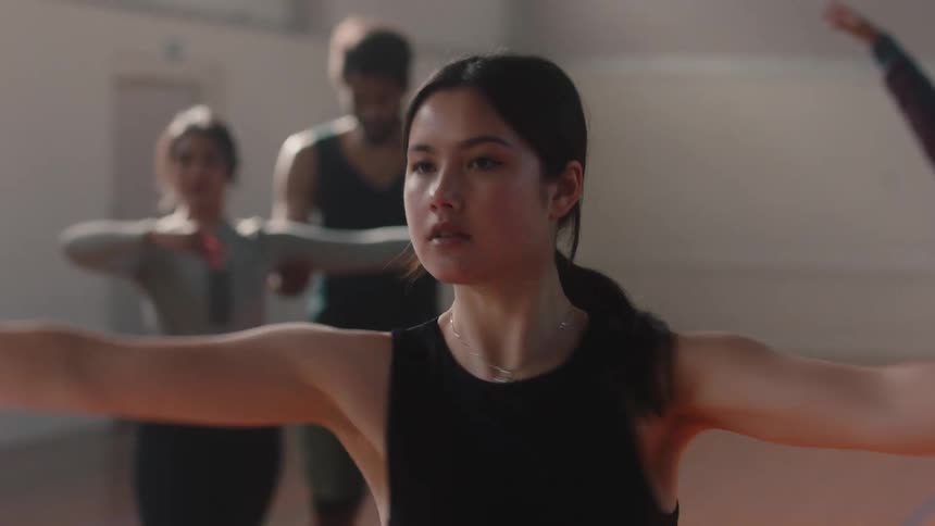 A teenager in a dance class practicing with other around her