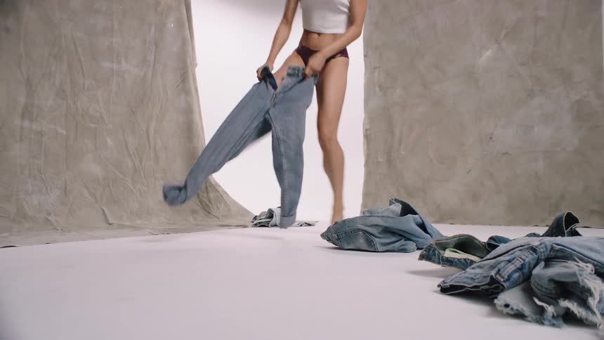 A model changes from shorts to jeans and walks out of the studio