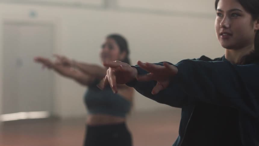Young women with arms extended forward flexing their fingers in stretches