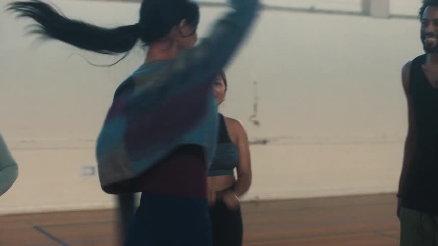 A woman dancing and some people around her are smiling at her