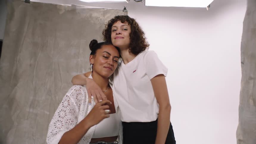 Three women model clothing in a tiny room with gray backdrops