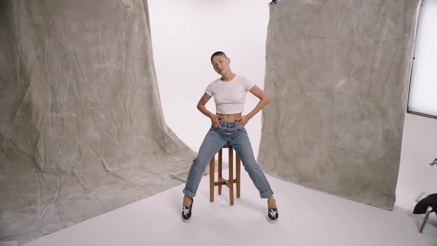 Woman takes different poses on stool in photography studio