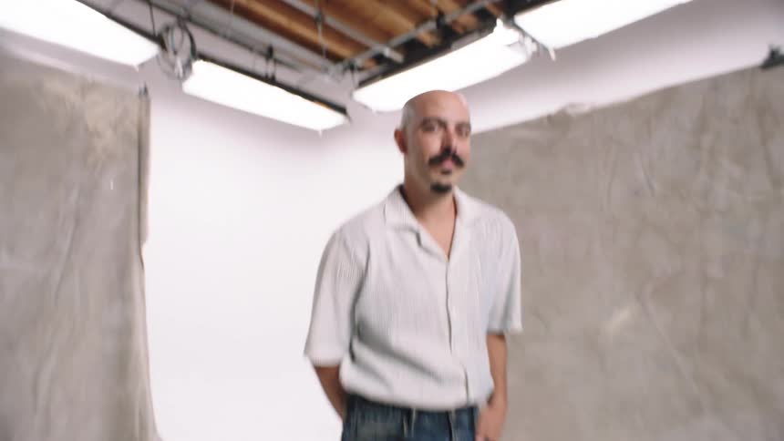 Man posing for camera on an indoor set white cyc photo studio tranistion denim