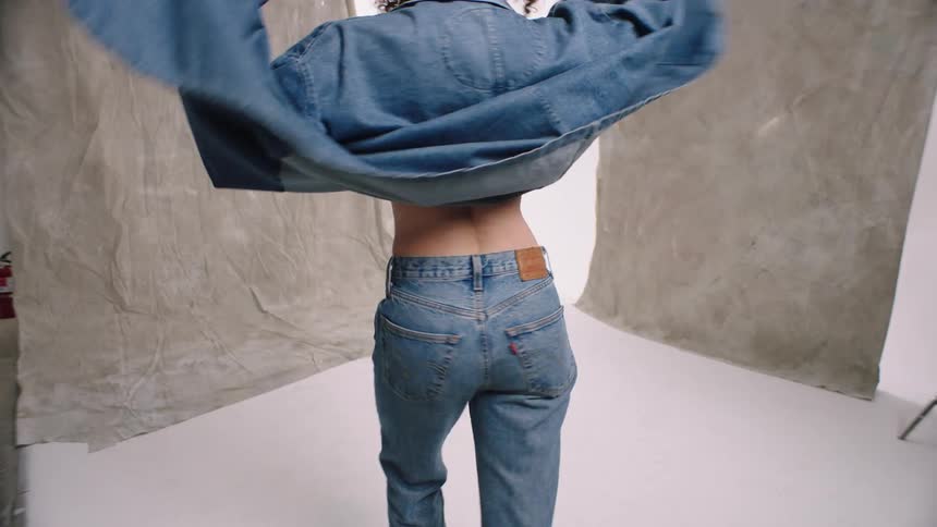 Model wearing denim walks back and forth while posing in photography white cyc studio woman dancing denim studio photoshoot Wrangler levi jeans