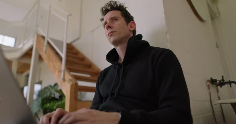 A man operating his computer while sitting in his living room