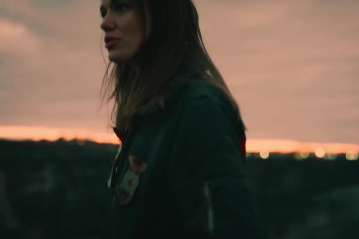 Woman feeling loved wearing a jacket in an open field under the evening sky