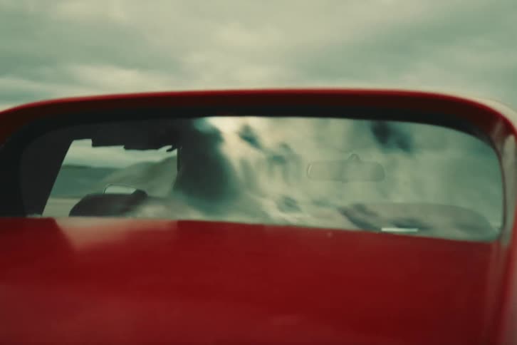 A person driving a red car at high speed