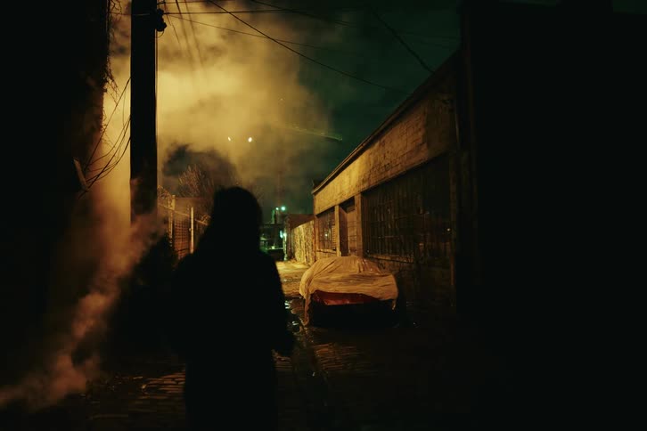 A person walking down an alley at night in the suburbs