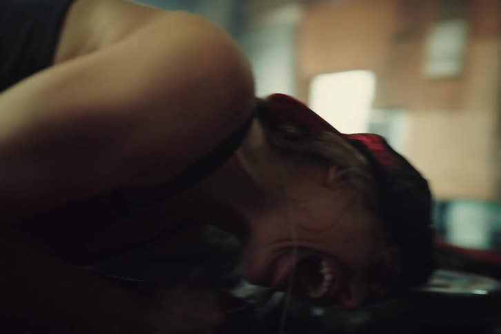 A woman mechanic is working on the engine of a red car and gets nervous