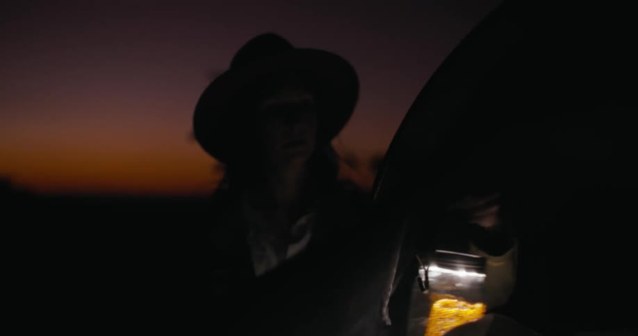 Woman hanging a lantern on her tent at dusk