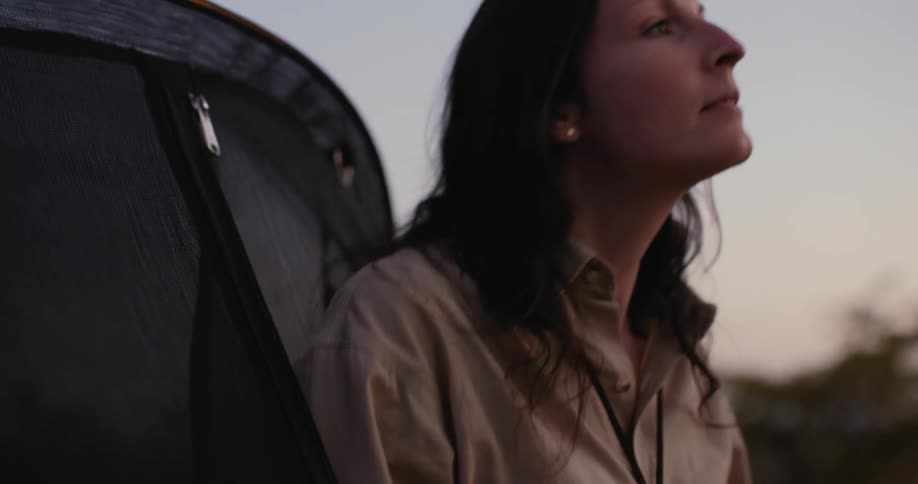 A woman camping in nature during sunset