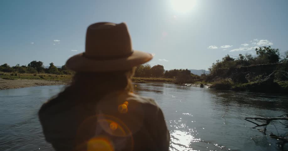 Woman riding down the river on a boat during a sunny day as she takes pictures