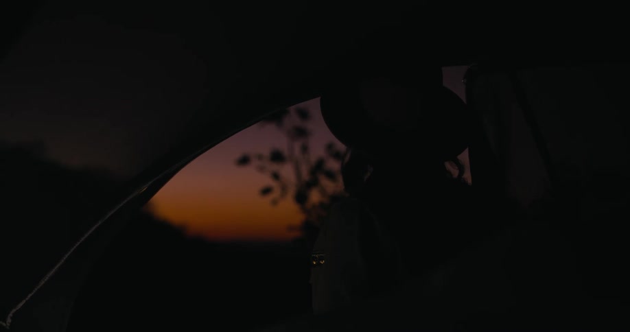 Woman gazes into sunset from her tent at dusk