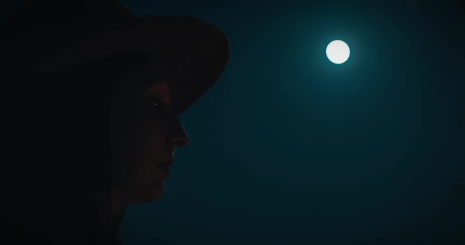 A womans face looking at the bright moon in the sky