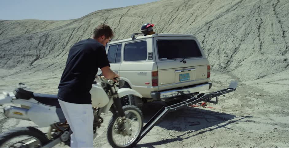 Man unloading his motocross bike from a truck in a natural setting